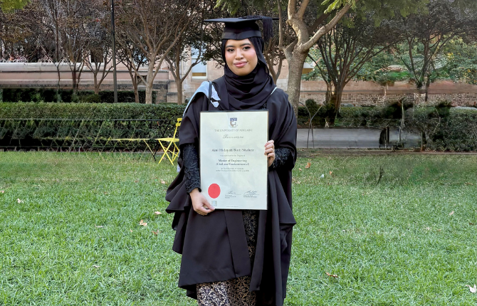A smiling girl hold her parchment on graduation day
